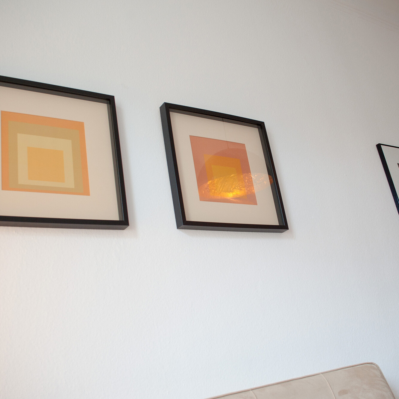 Drei gerahmte Bilder an der Wand eines Therapieraums, darunter Farbflächen und ein Schwarz-Weiß-Foto – klare, ruhige Atmosphäre mit persönlicher Note