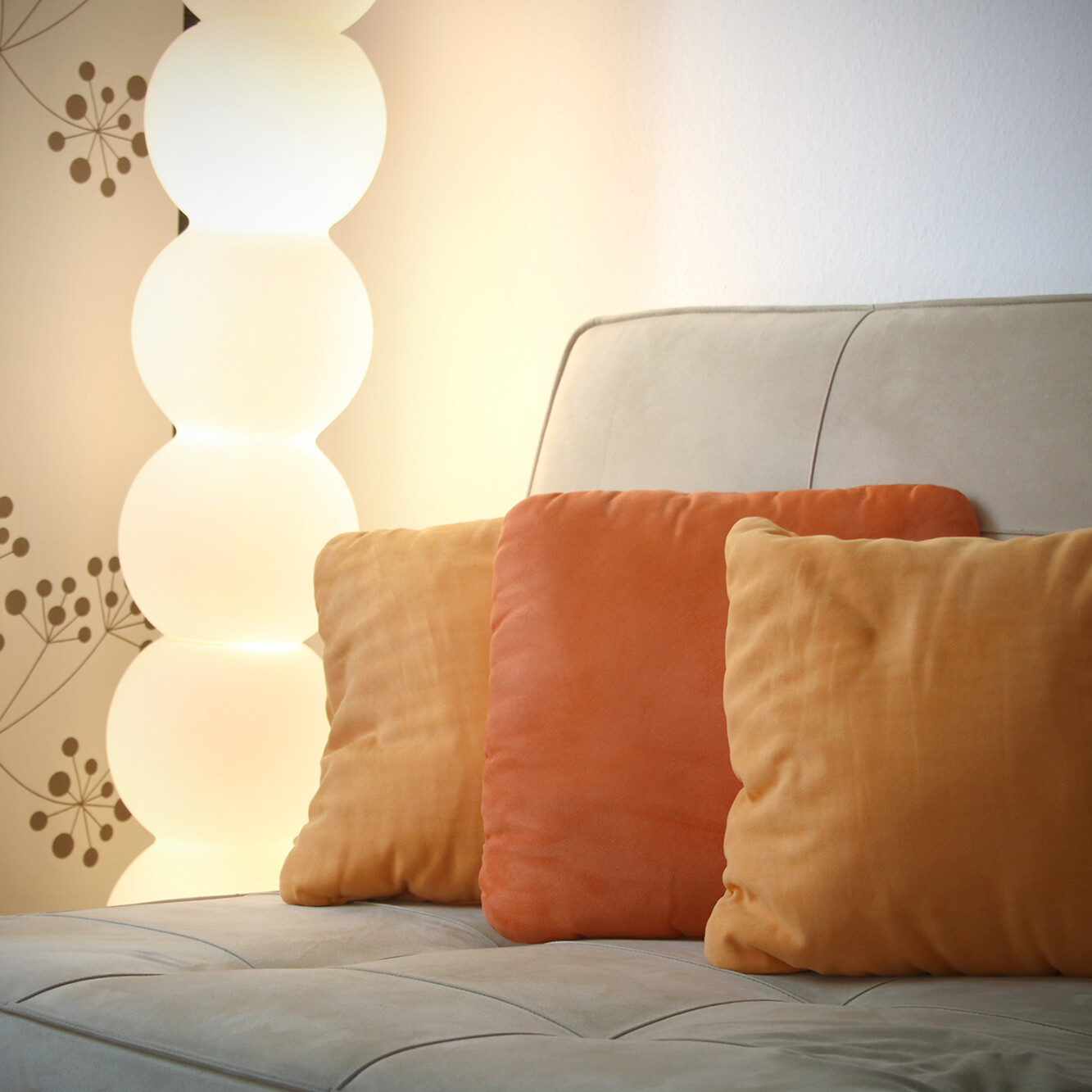 Therapiesofa mit orangefarbenen Kissen und sanfter Stehlampe – einladende Atmosphäre für Gespräche und psychotherapeutische Begleitung