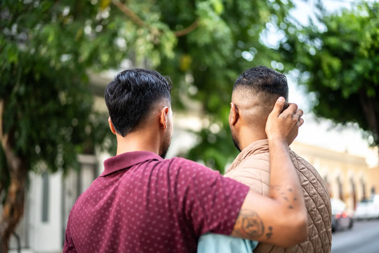 Zwei Menschen gehen nebeneinander, einer legt dem anderen beruhigend die Hand auf den Nacken
