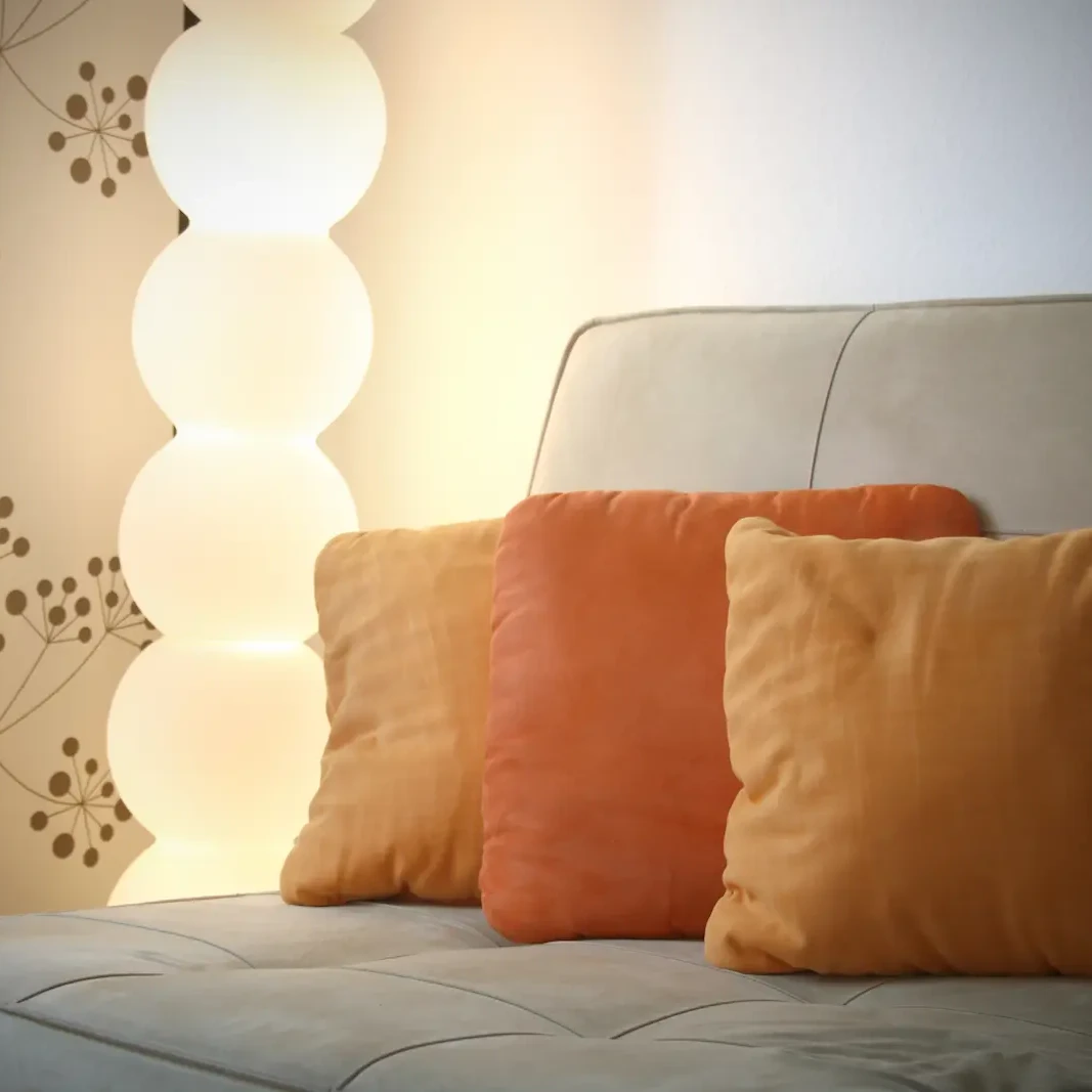 Bequemes Sofa mit orangefarbenen Kissen und Stehlampe im Praxisraum