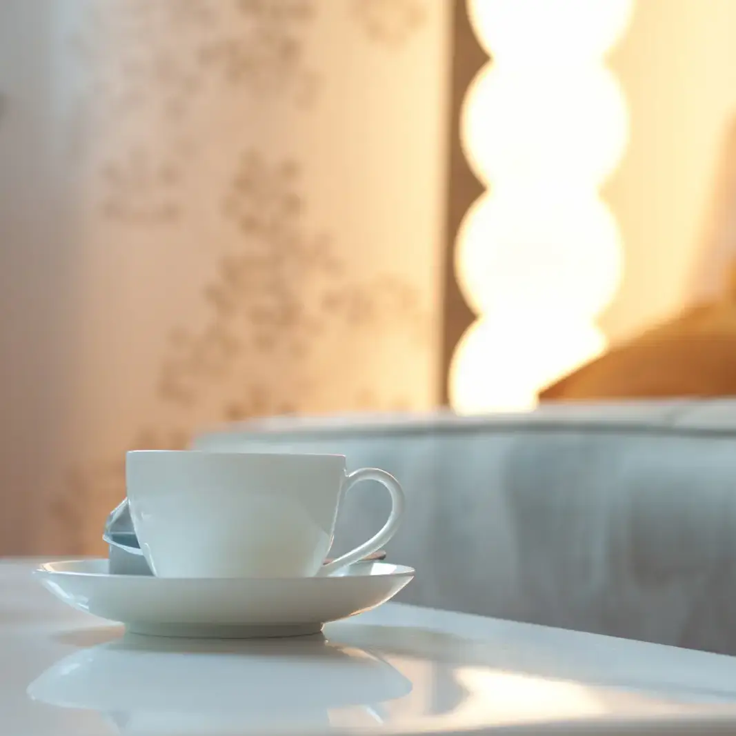 Weiße Tasse auf dem Tisch vor einem Sofa in warmem Licht